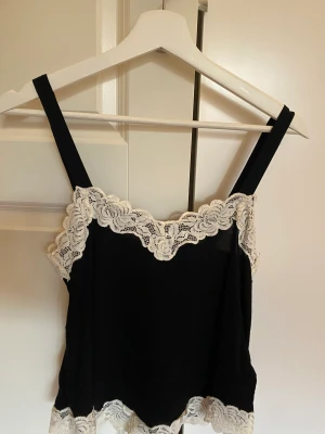 Spetslinne  - Jättesött linne från H&M inköpt i Polen. Svart chiffong med vit spets längs urringningen