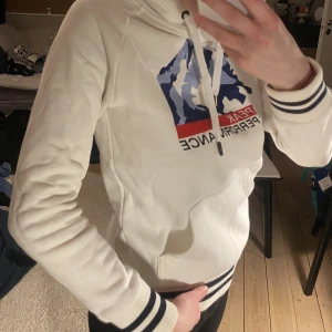 Peak Performance Hoodie - Knappt använd hoodie från Peak med tryck. Stilren och snygg. Saknar nedersta delen på ett av snörena. 