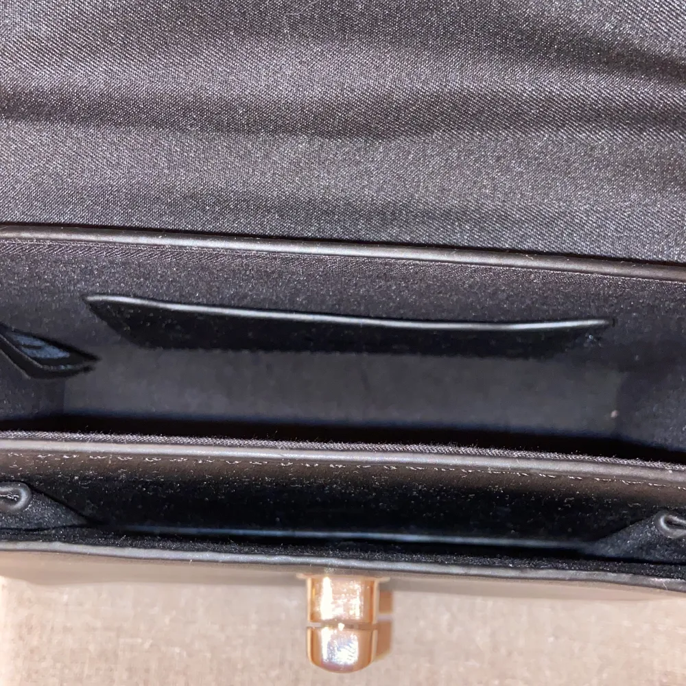 En svart handväska med silvrig kedja, helt oanvänd och i nyskick, den har två stora fack med ett mindre fack i ena, super söt fast säljer pga kommer inte till användning . Väskor.