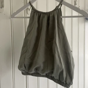 Ljusgrönt linne i ”silke” - Ljusgrönt croppat linne med högkrage och fin knytning i ryggen. Jättefin men bara använd nån gång. Materialet ser ut silkes liknande ut. Strl S.