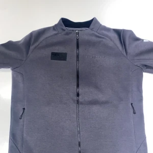 Sail Racing Defender Tech Zip Jacket (Herr) - Storlek Medium. Nästan helt ny, Bara använts några gånger. Skick 9/10. Säljer eftersom den är för stor. Original pris - 1300kr. Säljer billigt eftersom jag vill göra av mig med den och för att jag inte har kvittot för den.