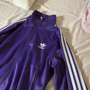 Adidas kofta lila  - Mörk lila adidas kofta med 3 vita linjen på sidan om passar folk från small till medium till och med xxs kanske