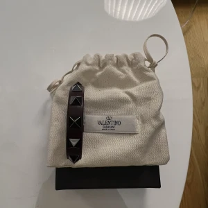 Valentino armband - Säljer nu mitt fina valentino armband i vinröd färg, väldigt mörk och påminner om den svarta färgen väldigt mycket. Helt ny med allt og, låda, dustbag, extra nitar osv. Fast pris på 1700 sek, bud från 1500 sek.