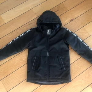 Hummel vinterjacka 164 - Svart vinterjacka från Hummel, köpt på Kidsbrandstore.  Sparsamt använd, ser ut som ny! Ej tvättad.  Snölås i ärmen, reflex bak samt fram.  Revär med Hummel på ärmarna.  Storlek 164