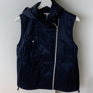 Väst från Filippa K Sport  - Väst i mörkblått från Filippa K Sport. Strl XS men passar en S lika bra. Avtagbar luva. Fint skick, inget att anmärka på!