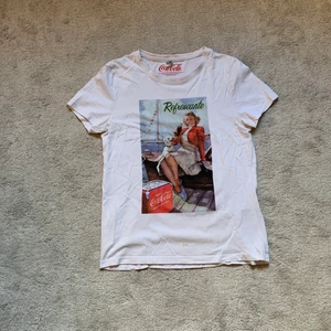 Grafisk coca cola t-shirt  - Väldigt fin T-shirt från coca cola. Använd ett par gånger, den har dock en fläck på underdelen, men tror den kan gå bort relativt lätt<3 Kan mötas upp eller skicka 