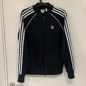 Adidas sweat jacket  - Svart Adidas sweat jacket i storlek 38. Använd fåtal gånger. Har två fickor på framsidan med dragkedja. Inga defekter, är som ny. Nypris 600. Hämtas i Stockholm eller skickar mot frakt. Vid frakt kan priser på tröjan diskuteras. 