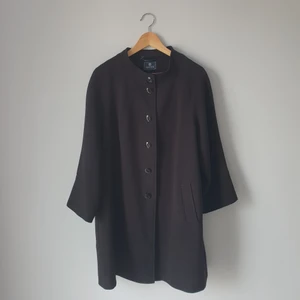 Kappa i storlek 46 - En fin svart kappa, med knappar, rosa insida, 3/4 ärmar. Storlek 46 65% polyester, 31% viskos och 4% spandex. Insida 100% polyester.