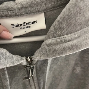 Juicy ziphoodie storlek M - En grå Juicy Couture tröja i storlek M. Den är i väldigt bra skick, knappt använd. (Tryck inte på köp nu!! Skriv till mig istället)