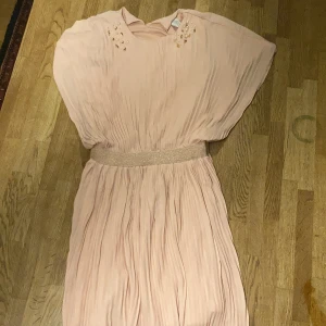  Klänning  -  En rosa klänning med pärlor på. Jag säljer den för att den är lite för stor för mig och inte riktigt min stil.