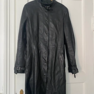 Vintage skinnkappa   - Svart vintage kappa i skinn. Kan användas som både klänning och kappa. Italiensk storlek 44 men skulle säga att den passar en Small. 