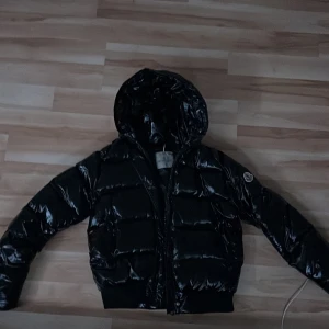 Moncler Maya Svart dunjacka - En perfekt jacka för vintern då den är väldigt varm, storlek 5 passar en kille 175, tjej passar 150 cm. Säljer denna då den är för liten tyvärr!