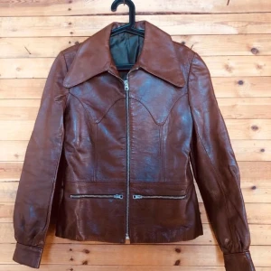 70-tal Skinnjacka Malung Vintage - Jofama Skinnjacka, 70-tal av Karallus Falk. Snygga detaljer, grova dragkedjor och snitt. Mycket bra skick. Small, dammodell. Byst: 45  Axel-Axel: 39 Längd: 61 Armlängd: 62