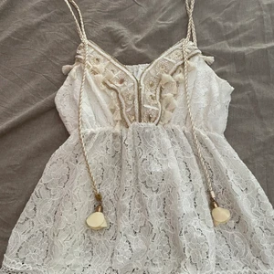 Vit topp - En vit topp i storlek one-size med guld detaljer! Aldrig använd och köpt i Spanien. Sälje pga att den inte kommit till användning. 