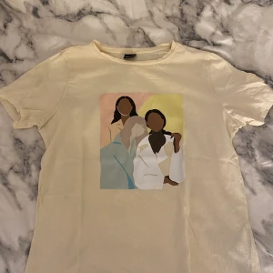 T-shirt med tryck Gina Tricot - En beige t-shirt med tryck från Gina Tricot. Köparen står för priset av frakten. 