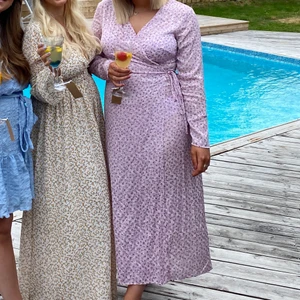 Blommig långklänning  - Ljus rosa/lilla långklänning med omlottknytning i midjan. Storlek 40. Inköpt på hm februari 2021 och har användts endast en gång 