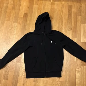 Svart Ralph Lauren zip hoodie - En ralph lauren zip i storlek small. I väldigt bra skick, har bara använts ett fåtal gånger. 