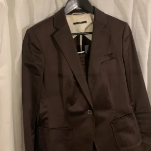 Kostym Hugo boss  - Mörkbrun kostym i dam från  hugo boss. Passar 36/38. Köpt second hand för 900kr. Inga tecken på användning, jag har aldrig använt den då den inte passar. Pris kan diskuteras vid snabb affär! 