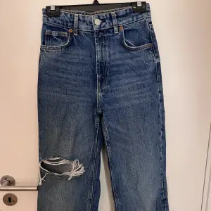 Blå jeans från zara med hål på knäet.