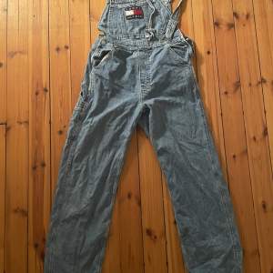 Vintage Tommy Hilfiger hängselbyxor i ljust jeans. Modell: Lot i strl M (Fläck på loggan)
