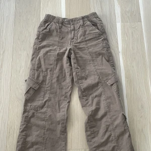 Lågmidjade bruna cargo byxor - Säljer nu mina BDG Brown Y2K Low Rise Cargo Pants från Urban outfitters i storlek xs då det inte längre är min stil. Endast använda några få gånger och är i bra skick. Köparen står för frakt! Meddela om du har några frågor💕