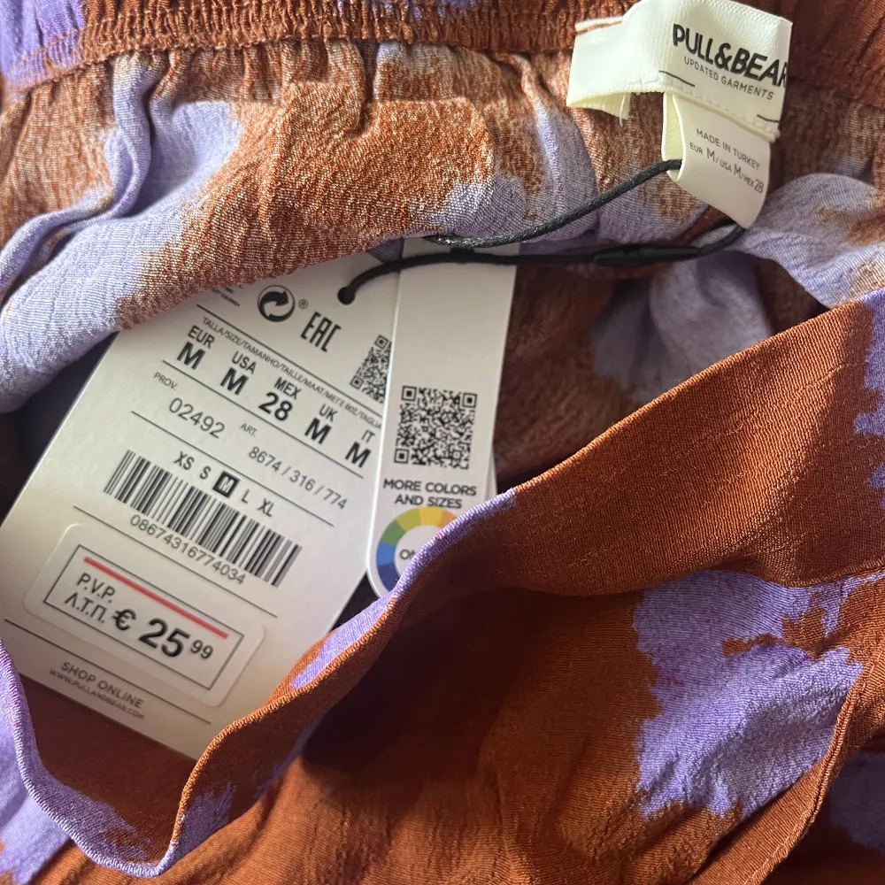 Omlottbyxor och linne med knyt, Batikmönstrad i rödbrun och blålila från PULL&BEAR. Bild 1 är lånad från deras hemsida. Köpt förra året och aldrig använd. Storlek Medium, funkar även för en som i vanliga fall har Small då det är resår och knyt. . Toppar.