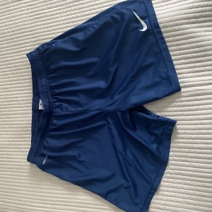 Nike shorts  - Blå Nike shorts, storlek L men skulle säga mer som M, använda en gång. Pris går att diskuteras. Kan även skicka mer bilder. 