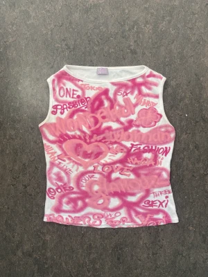 Topp med rosa graffiti-liknande tryck - Rosa tryck på framsidan, vit baksida. Gott skick. 