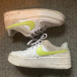 Vita air force one skor med neon grön/gul swoosh. De är höga i sulan och de är i okej skick. På tredje bilden ser man att tyget har gått sönder inna lite vid hälarna.