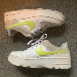 Neon grön/gula nike skor - Vita air force one skor med neon grön/gul swoosh. De är höga i sulan och de är i okej skick. På tredje bilden ser man att tyget har gått sönder inna lite vid hälarna.