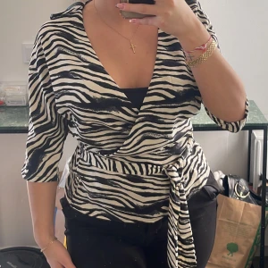 Zebra tröja  - Tröja i zebra mönster med knyte längst ner. Har en urringning 