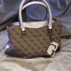 Guess väska  - Äkta guess väska köpt för 2 år sen men bara använd ett halvår sen har den bara stått, en bra väska både om man behöver få plats med mycke ut och passar till allt älskar verkligen denna men måste säljas pga att jag har för många väskor, köpt för 1800kr
