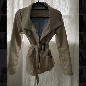 Kort trenchcoat - VÅRJACKA Kort trenchcoat med skärp i midjan!  Säljer då den tyvärr är för liten för mig.. Inga fläckar eller liknande !❤️
