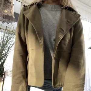 Grön kappa - Strl 40 men passar xs. Har sprättat bort alla knappar för tyckte inte om att de var svarta, dom finns kvar och går att sy dit igen❤️ Ett litet hål på ena axeln i yttertyget (alltså inte i fodringen) efter ett försök att sprätta bort flikarna på axlarna