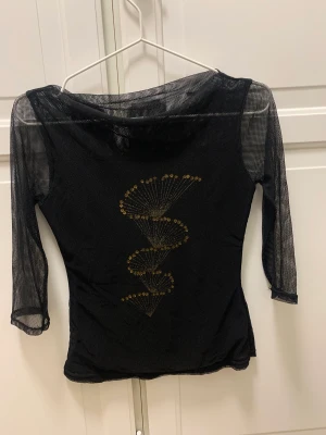 Topp med mesh - Svart topp med mesh och pärldetaljer