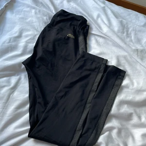 Träningstights - Svarta träningstights med grå rand på sidan och knytning i midjan. Supersköna o superfina. Säljer pga att jag har för mycket träningskläder. 🖤 