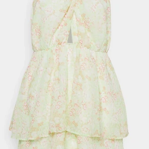 Volang Klänning - Kort Pastellfärgad Klänning med volanger. Öppen rygg med knytning. 