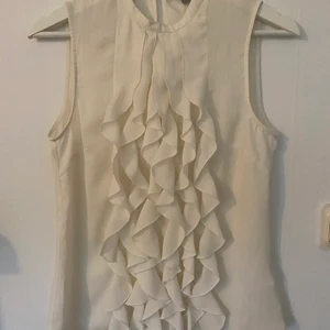 Blus från H&M strl 34 - Cremevit top, lite lätt genomskinligt tyg, knapp bak i nacken. Använd men i bra skick.