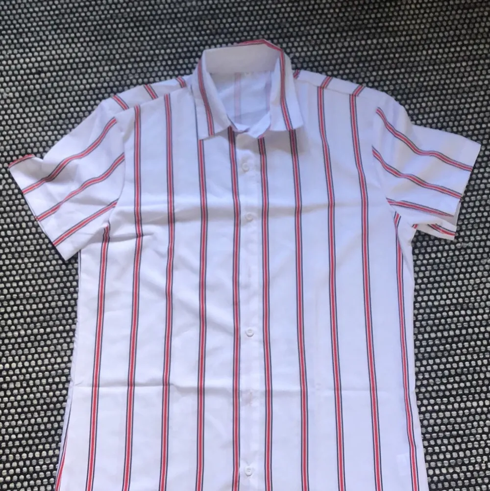 En väldigt fin kortärmad skjorta. Den är vit och röd. Den är i storlek M. Den är i väldigt bra skick då den aldrig har används!. Skjortor.