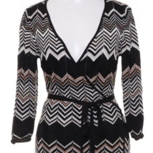 Omlottklänning Missoni  - Storlek S En riktigt godbit från Missoni som Lindex hade ett samarbete med. Den här klänning är i omlottmodell i det klassiska Missoni mönstret i brunt och beige. 100% viscos  Sparsamt använd, inga anmärkningar.  Pris 550 kr 