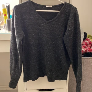 Stickad tröja - Stickad tröja i gråsvart färg med V-ringad hals. Superfin. Lite nopprig och använd så inte i världens nyaste skick, men den funkar absolut. Säljer för 30kr+frakt. 