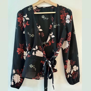 Nelly Black wrap blouse - Black wrap blouse with floral pattern.  Great condition Never worn (tag cut off)  Size: Small 