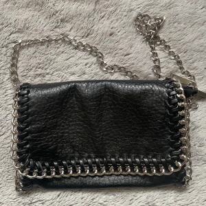 Svart väska  - En svart Axelremsväska med kedja runt om. Knappt använt 