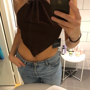 Brun topp - Brun topp, öppen i ryggen, knyts med två band. Silkes material och strl. 38. 