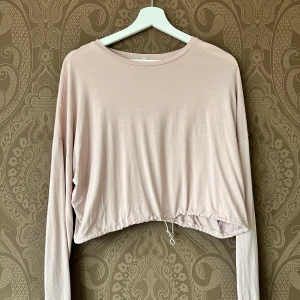 Långärmad tröja - En långärmad tröja i ”smutsrosa” som går att dra åt i midjan om man vill ha en kortare tröja. Ganska använd men i bra skick och fräsch, från Nelly🫶🏻🫶🏻