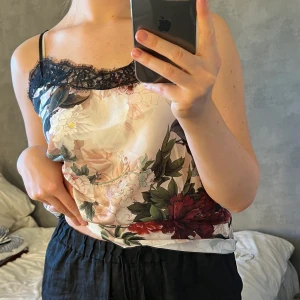 Blommigt linne med spets - Supergulligt och snyggt linne i satin med spetskant! Oklart vart det är köpt och vilken storlek men passar mig som är S/M! Den är stretchig och har justerbara band. Aldrig använt.🤍 Hör av dig för fler bilder eller vid eventuella frågor!☺️