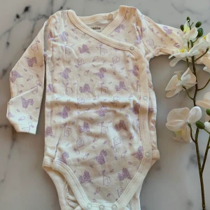 Ny långärmad body strl 62-68 - Ny och ej upptvättad men inga lappar kvar.  Vit långärmad body med lil tryck, strl 62/68. 