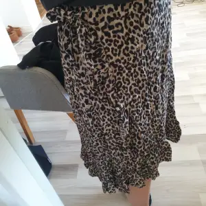 En lång leopardmönstrad kjol från Lindex. På sidan så är det volanger och en rosett, som man kan knyta om och själv välja hur man vill ha den. Kjolen har även resor runt midjan