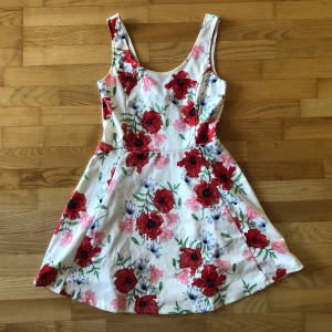 Klänning med blommor - Vit klänning med blommor, polyester och elastan. Bra skick.