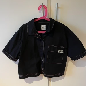 Croppad kortärmad vans skjorta  - En kortärmad skjorta med en rosa sömm från vans strl M men passar som en S om man vill ha den lite mer oversize. 
